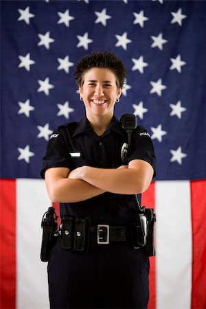 female police officer happy - Portrait of mid adult Caucasian policewoman standing with arms crossed and American flag as backdrop smiling at viewer. Photographie de stock - Aubaine LD & Abonnement, Code: 400-03940756