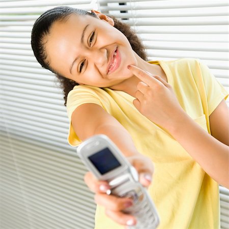 simsearch:400-05012508,k - African American preteen girl holding cell phone out to viewer and smiling. Foto de stock - Super Valor sin royalties y Suscripción, Código: 400-03940883