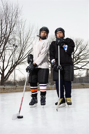 Two boys in ice hockey uniforms holding hockey sticks standing on ice rink in ice skates. Stock Photo - Budget Royalty-Free & Subscription, Code: 400-03943509