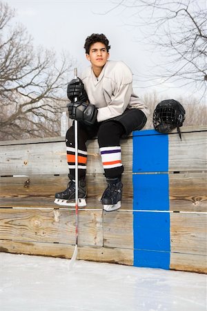 Boy in ice hockey uniform holding hockey stick sitting on sidelines. Stock Photo - Budget Royalty-Free & Subscription, Code: 400-03943516