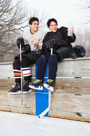 Two boys in ice hockey uniforms sitting on ice rink sidelines pointing and looking. Stock Photo - Budget Royalty-Free & Subscription, Code: 400-03943517