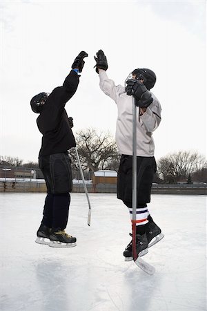 Two boys in ice hockey uniforms giving eachother high five on ice rink. Stock Photo - Budget Royalty-Free & Subscription, Code: 400-03943518