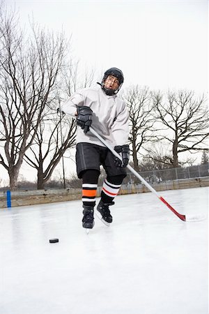 Boy in ice hockey uniform skating on ice rink moving puck. Stock Photo - Budget Royalty-Free & Subscription, Code: 400-03943510