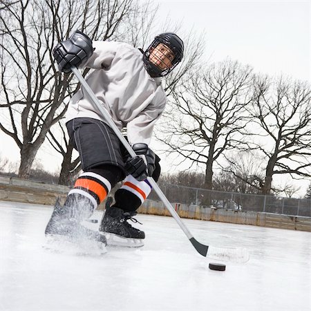 Boy in ice hockey uniform skating on ice rink moving puck. Stock Photo - Budget Royalty-Free & Subscription, Code: 400-03943511