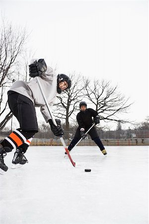 Two boys in ice hockey uniforms skating on ice rink moving puck. Stock Photo - Budget Royalty-Free & Subscription, Code: 400-03943513