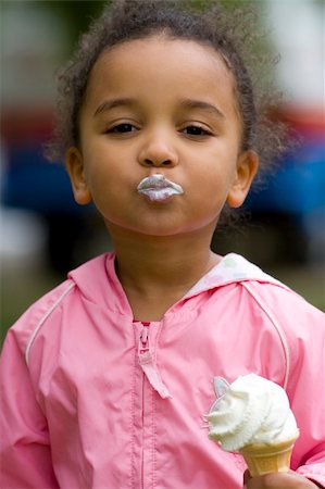 A beautiful mixed race little girl eating an ice cream and blowing a kiss to the camera Stock Photo - Budget Royalty-Free & Subscription, Code: 400-03954753