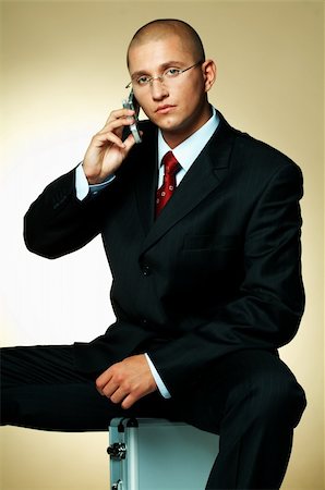 simsearch:400-03954954,k - A businessman wearing black suit, using cell phone and sitting on case Stock Photo - Budget Royalty-Free & Subscription, Code: 400-03955074