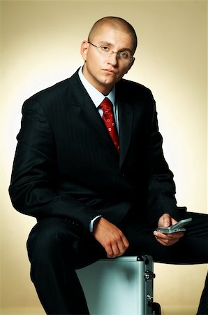 simsearch:400-03954954,k - A businessman wearing black suit, using cell phone and sitting on case Stock Photo - Budget Royalty-Free & Subscription, Code: 400-03955072