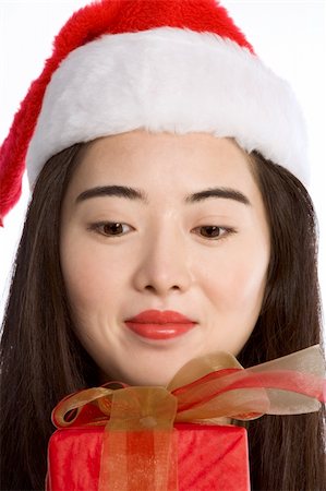 simsearch:622-06190925,k - Asian girl in Santa hat looking on wrapped gift-box Stock Photo - Budget Royalty-Free & Subscription, Code: 400-03951668