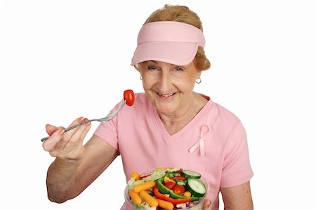 A senior woman in pink with Breast Cancer Awareness ribbon, eating healthy salad.  Isolated on white. Stock Photo - Budget Royalty-Free & Subscription, Code: 400-03969123