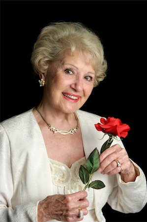 A beautiful, successful senior lady dressed in formalwear holding a red rose. She has perfect teeth. Photographie de stock - Aubaine LD & Abonnement, Code: 400-03969177