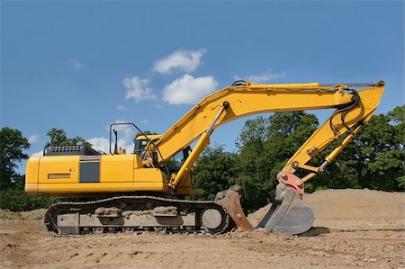 simsearch:700-05662628,k - Yellow digger standing idle on a construction site, with trees and a blue sky to the rear. Stock Photo - Budget Royalty-Free & Subscription, Code: 400-03961835
