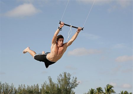 A young man flying through the air on a parasail. Stock Photo - Budget Royalty-Free & Subscription, Code: 400-03970477