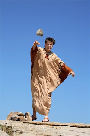 Depiction of ancient man throwing rock or stone.   concept sticks and stones, sin, or historical reenactment.  Rock shows motion. Stock Photo - Budget Royalty-Free & Subscription, Code: 400-03987544