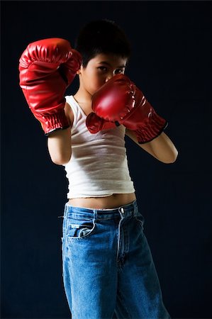 Young asian boy with serious expression wearing red boxing gloves standing on black background Foto de stock - Super Valor sin royalties y Suscripción, Código: 400-03995589