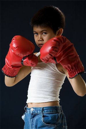 Young asian boy with serious expression wearing red boxing gloves standing on black background Foto de stock - Super Valor sin royalties y Suscripción, Código: 400-03995917
