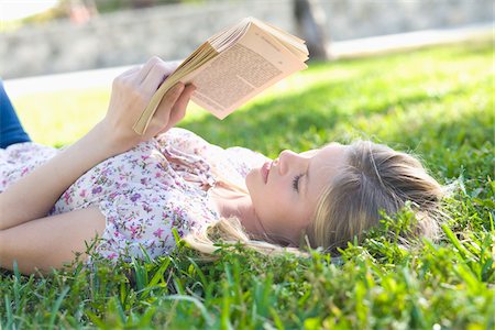 Close-up of Woman Lying on Grass, Reading Book Stock Photo - Premium Royalty-Free, Code: 600-05822156