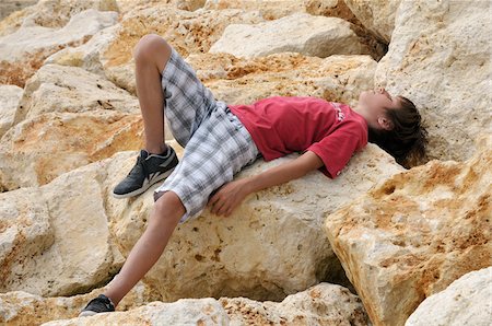 Boy Lying on Rocks, Ile de Re, France Stock Photo - Premium Royalty-Free, Code: 600-06334392