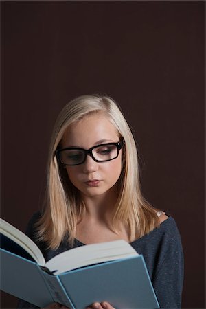 simsearch:600-05821994,k - Portrait of Blond, Teenage Girl wearing Eyeglasses and Reading Book, Studio Shot on Black Background Stock Photo - Premium Royalty-Free, Code: 600-06438956