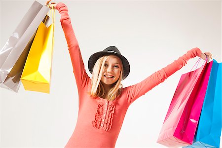 simsearch:600-06334388,k - Low Angle View Portrait of Blond, Teenage Girl wearing Hat and holding Shopping Bags in Air, Studio Shot on White Background Foto de stock - Sin royalties Premium, Código: 600-06438974