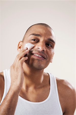 Man Applying Lotion to his Face in Studio with White Background Stock Photo - Premium Royalty-Free, Code: 600-06485951