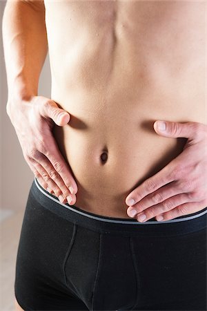 Close-up of Young Man in Boxer Briefs Touching Stomach in Studio Stock Photo - Premium Royalty-Free, Code: 600-06486009