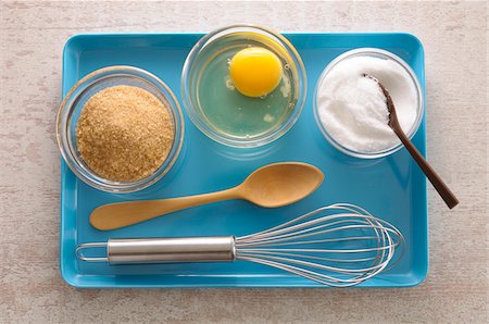 Overhead View of Brown Sugar, White Sugar and Raw Egg in Bowls with Wooden Spoon and Whisk on Tray, Studio Shot Stock Photo - Premium Royalty-Free, Code: 600-06486043