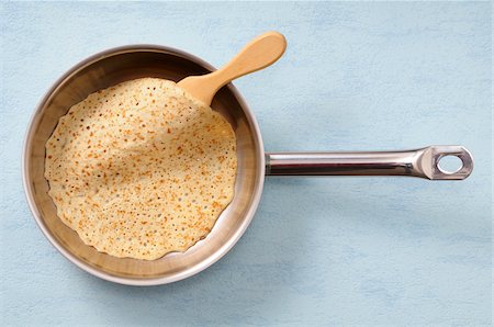 pancake - Overhead View of Pancake in Frying Pan with Spatula on Blue Background, Studio Shot Stock Photo - Premium Royalty-Free, Code: 600-06486073