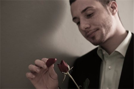 simsearch:700-07278871,k - Portrait of Young Man Plucking Petals from Red Rose, Studio Shot Photographie de stock - Premium Libres de Droits, Code: 600-06486236