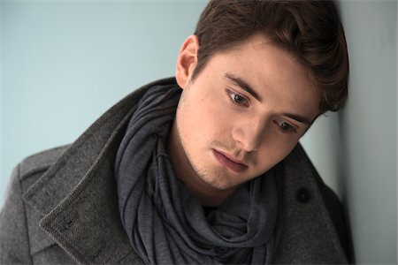 sad and missing someone - Head and Shoulder Portrait of Young Man wearing Grey Scarf and Jacket, Absorbed in Thought, Studio Shot on Grey Background Stock Photo - Premium Royalty-Free, Code: 600-06486254