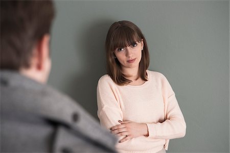 focus on background - Portrait of Young Woman Standing in front of Young Man, Looking at him Intensely, Studio Shot on Grey Background Stock Photo - Premium Royalty-Free, Code: 600-06486267