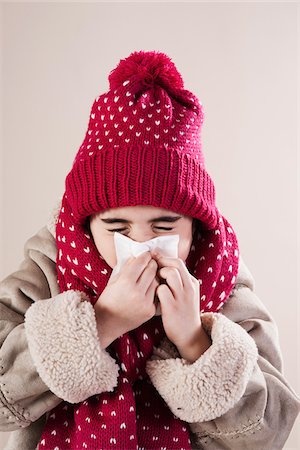 Portrait of Girl wearing Hat and Scarf Blowing Nose in Studio Stock Photo - Premium Royalty-Free, Code: 600-06486410