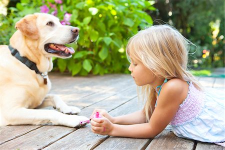 Little girl painting the claws of a dog with bright pink nail polish on a sunny summer afternoon in Portland, Oregon, USA Foto de stock - Sin royalties Premium, Código: 600-06531468