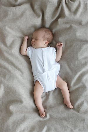 newborn baby girl in a white undershirt sleeping on a bed, Ontario, Canada Stock Photo - Premium Royalty-Free, Code: 600-06531989