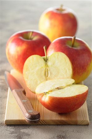 simsearch:600-06671821,k - Close-up of Red Apples on Cutting Board with Knife, One Cut in Half Photographie de stock - Premium Libres de Droits, Code: 600-06671823