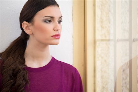 Young Woman Looking through Window, Studio Shot Stock Photo - Premium Royalty-Free, Code: 600-06685192