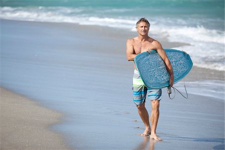 Mature Man Walking down Beach with Surfboard, USA Stock Photo - Premium Royalty-Free, Code: 600-06752297
