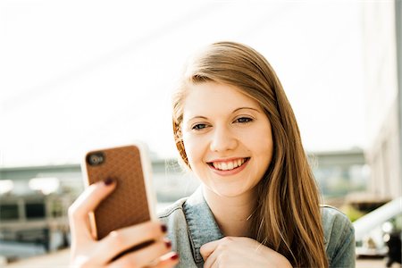 strawberry blonde - Young woman outdoors looking at smartphone Stock Photo - Premium Royalty-Free, Code: 600-06786801