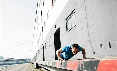 Mature man doing push-ups outdoors, on loading dock in front of warehouse, Mannheim, Germany Stock Photo - Premium Royalty-Free, Code: 600-06786858