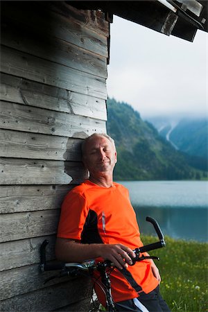 Mature Man leaning against Wooden Building with Mountain Bike, Vilsalpsee, Tannheim Valley, Tyrol, Austria Fotografie stock - Premium Royalty-Free, Codice: 600-06819415