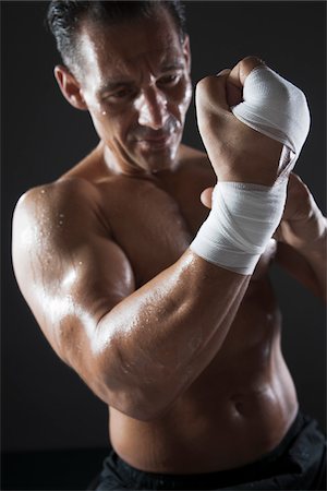 sports tape - Muscular Man Wrapping Hand with Sports Tape, Studio Shot Stock Photo - Premium Royalty-Free, Code: 600-06841763