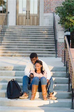 simsearch:400-05012508,k - Young couple sitting together outdoors on college campus steps, looking at smartphone, Florida, USA Foto de stock - Sin royalties Premium, Código: 600-06841936