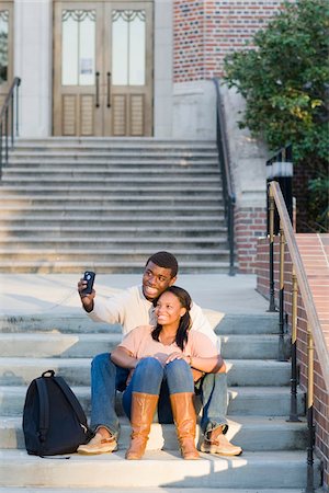 entre 19 y 20 años - Young couple sitting together outdoors on college campus steps, taking selfie with smartphone, Florida, USA Foto de stock - Sin royalties Premium, Código: 600-06841937