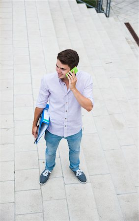 High angle view of young man standing outdoors, using cell phone, Germany Stock Photo - Premium Royalty-Free, Code: 600-06899945