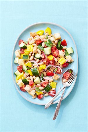 plate - Overhead View of Bread Salad with White Beans, Tomatoes, Peppers and Cucumber, Blue Background, Studio Shot Stock Photo - Premium Royalty-Free, Code: 600-06934971