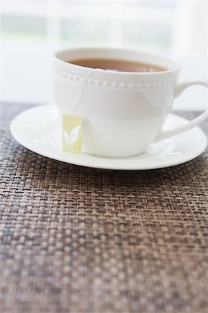 simsearch:600-07067016,k - Cup of tea in white porcelain cup with saucer and tea bag, studio shot Stock Photo - Premium Royalty-Free, Code: 600-07067018