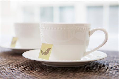 simsearch:600-07067016,k - Two white porcelain teacups with saucers and tea bags, studio shot Stock Photo - Premium Royalty-Free, Code: 600-07067022