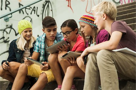 Group of children sitting on stairs outdoors, using tablet computers and smartphones, Germany Stock Photo - Premium Royalty-Free, Code: 600-07117175