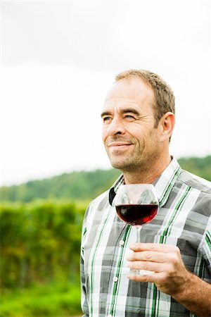 farmer looking at farm photos - Close-up of vintner standing in vineyard, holding glass of wine, Rhineland-Palatinate, Germany Stock Photo - Premium Royalty-Free, Code: 600-07148216