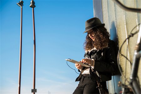 person with tablet - Teenage girl standing outdoors, wearing fedora and using tablet computer, Germany Stock Photo - Premium Royalty-Free, Code: 600-07310984